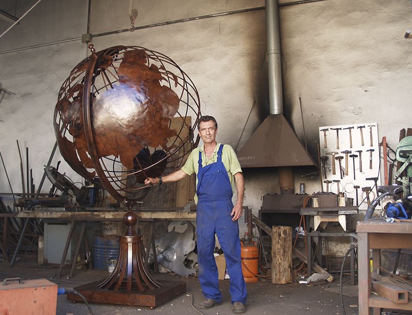 Vicente Gragera con su obra de Bola del Mundo en forja de hierro